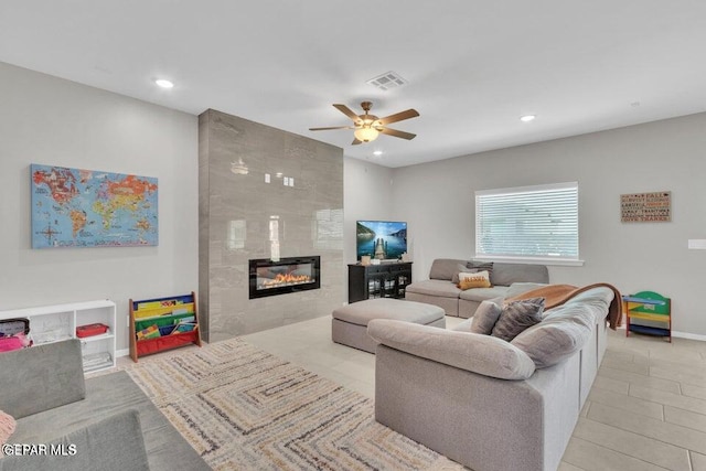 living room with ceiling fan and a tile fireplace