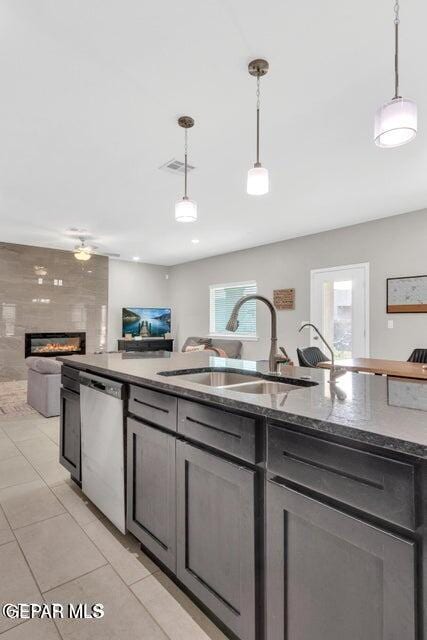 kitchen with dishwasher, sink, a large fireplace, and pendant lighting