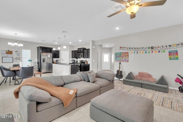 tiled living room with a healthy amount of sunlight, sink, and ceiling fan with notable chandelier