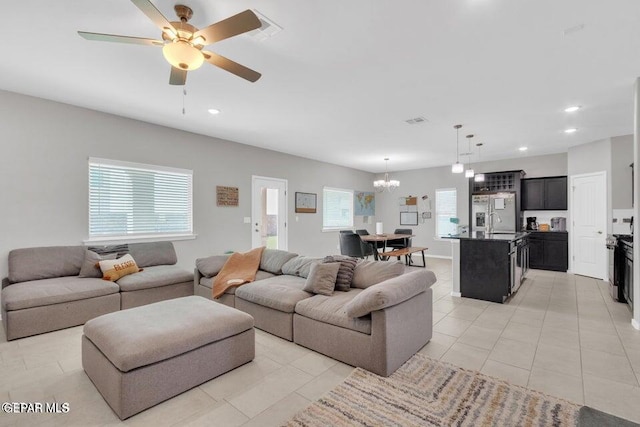 living room featuring ceiling fan with notable chandelier, plenty of natural light, and light tile patterned floors