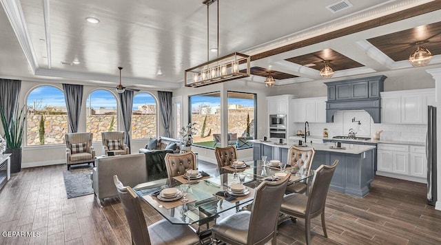 dining room with ceiling fan, coffered ceiling, beamed ceiling, ornamental molding, and dark hardwood / wood-style floors