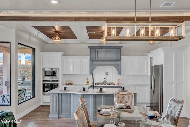 kitchen with appliances with stainless steel finishes, hardwood / wood-style floors, decorative light fixtures, and gray cabinetry