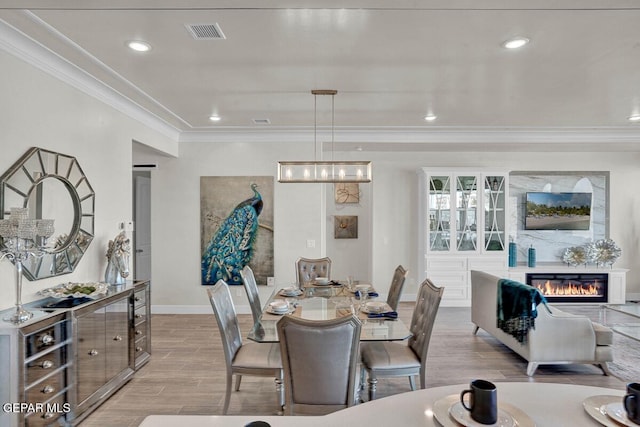 dining area with light hardwood / wood-style floors and crown molding