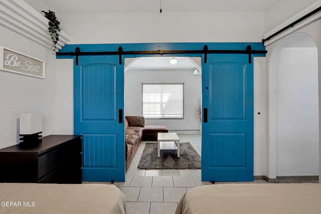 bedroom featuring light tile patterned floors and a barn door