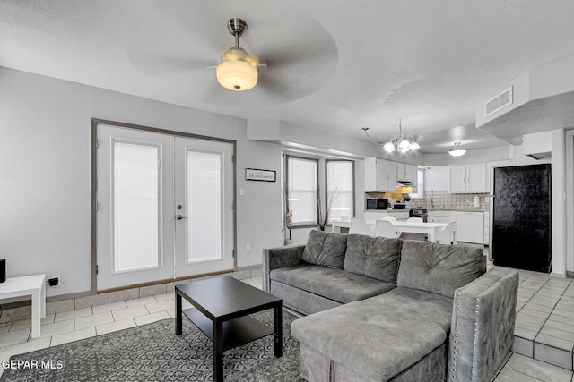 tiled living room with french doors and ceiling fan with notable chandelier