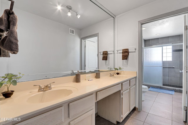 bathroom featuring toilet, tile patterned flooring, vanity, and a shower with door