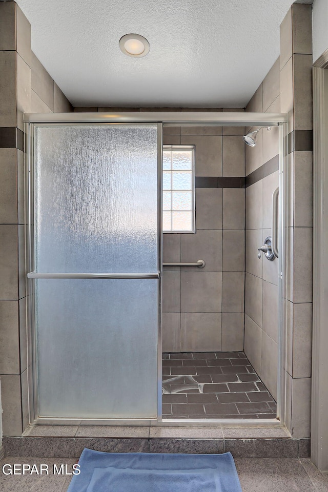 bathroom featuring a textured ceiling and an enclosed shower