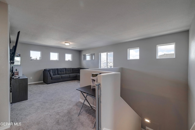 living room with a textured ceiling, light colored carpet, and plenty of natural light