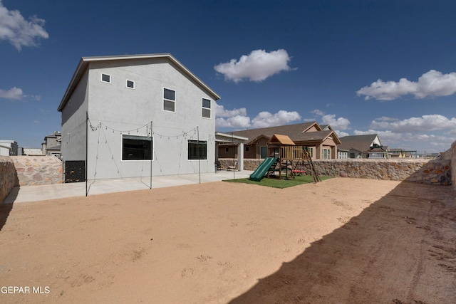 back of property with a patio area and a playground