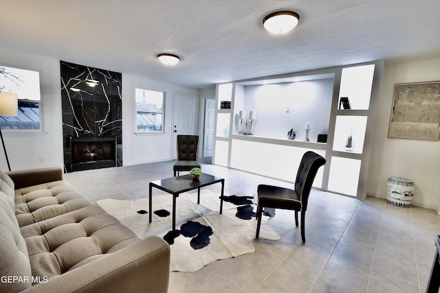 living room featuring a premium fireplace, light tile patterned flooring, and a textured ceiling