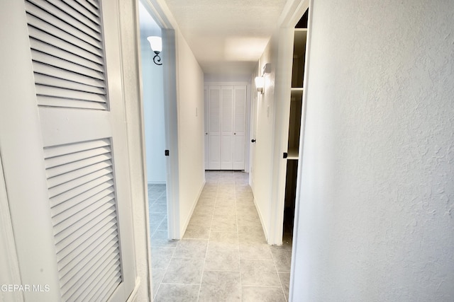 corridor featuring light tile patterned flooring and a textured ceiling