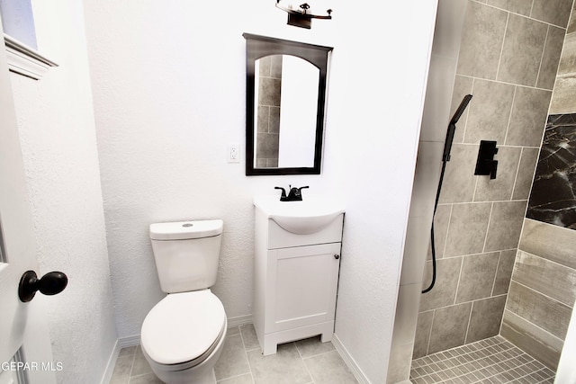 bathroom with tiled shower, tile patterned floors, vanity, and toilet