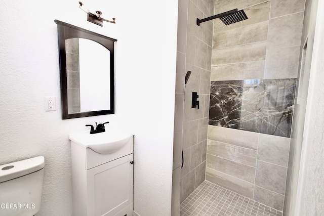 bathroom with a tile shower, vanity, and toilet