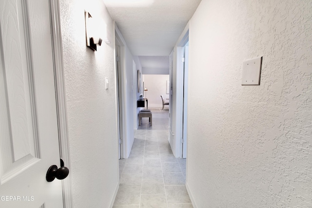 hall featuring light tile patterned floors and a textured ceiling