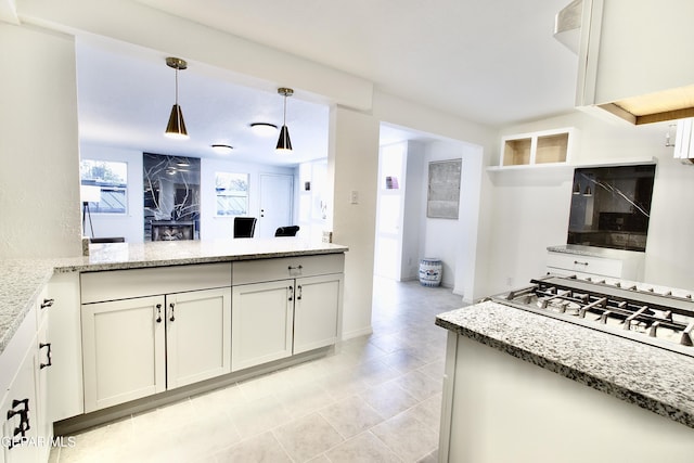 kitchen featuring white cabinets, hanging light fixtures, light stone countertops, light tile patterned floors, and kitchen peninsula