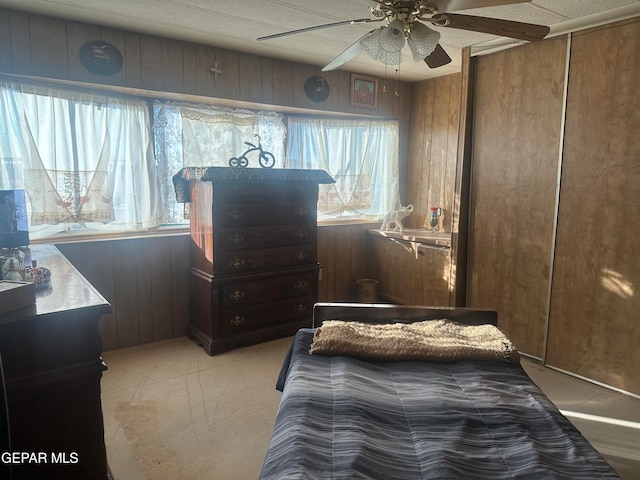 bedroom with wood walls, ceiling fan, and a closet