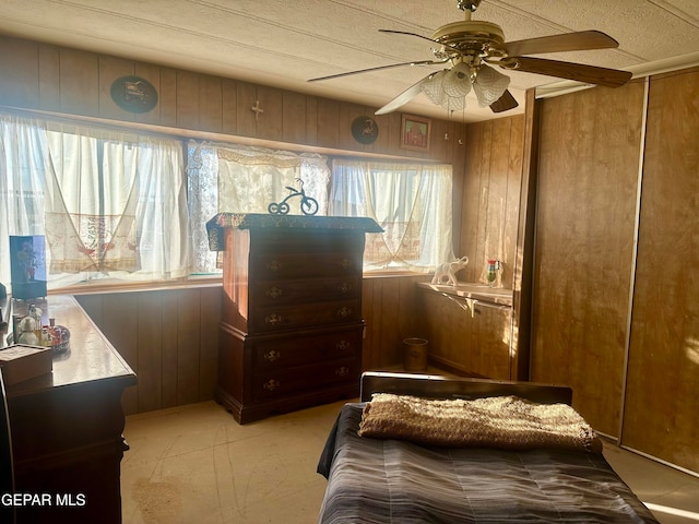 bedroom featuring wood walls and ceiling fan