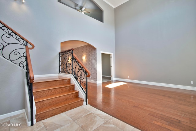 staircase with a towering ceiling, hardwood / wood-style flooring, and ceiling fan