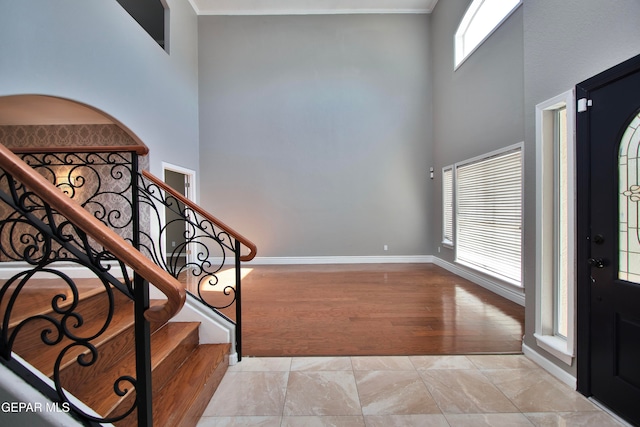 foyer entrance with a towering ceiling, crown molding, and light hardwood / wood-style floors