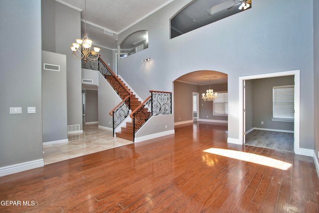 entrance foyer with an inviting chandelier, crown molding, hardwood / wood-style flooring, and a high ceiling