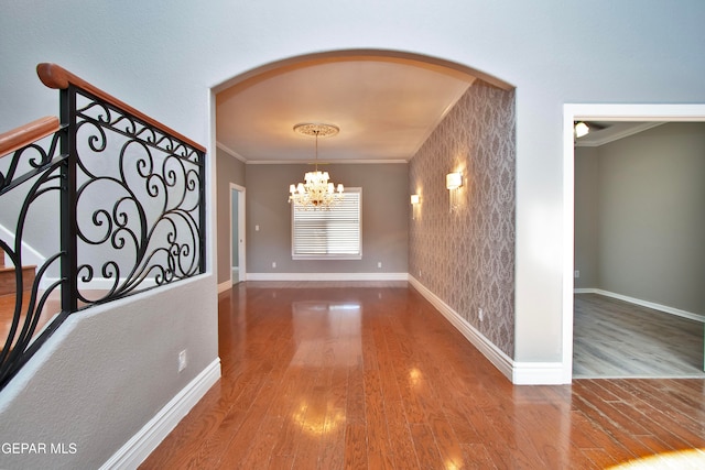 hall with ornamental molding, hardwood / wood-style floors, and a chandelier