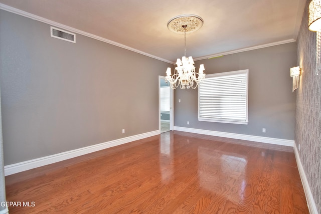 unfurnished room featuring crown molding, a notable chandelier, and wood-type flooring