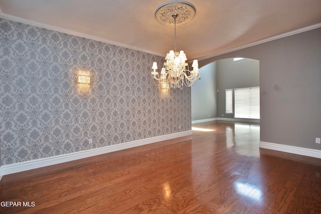 unfurnished room featuring a notable chandelier, ornamental molding, and dark hardwood / wood-style flooring