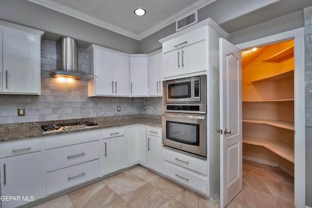 kitchen with wall chimney exhaust hood, stainless steel appliances, backsplash, crown molding, and white cabinetry