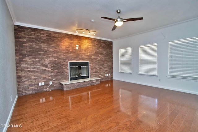 unfurnished living room featuring track lighting, ornamental molding, hardwood / wood-style floors, a fireplace, and ceiling fan