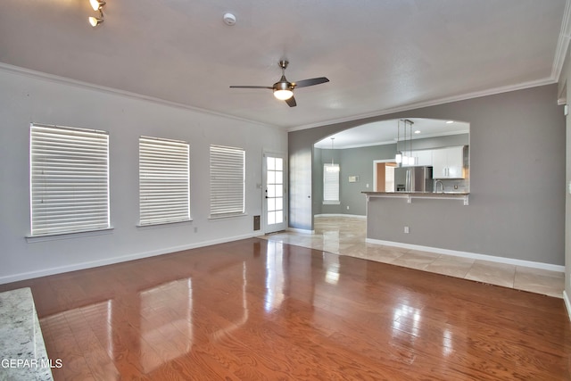 unfurnished living room with crown molding, light wood-type flooring, and ceiling fan