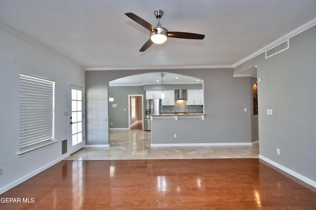 unfurnished living room featuring sink, crown molding, light wood-type flooring, and ceiling fan