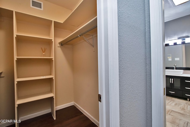 walk in closet with sink and hardwood / wood-style flooring