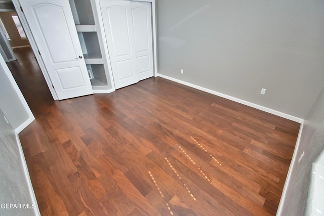 unfurnished bedroom with dark wood-type flooring and a closet