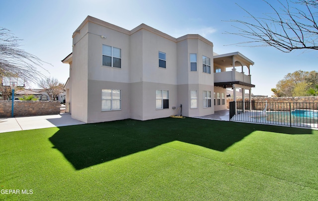 rear view of property featuring a patio, a lawn, and a balcony