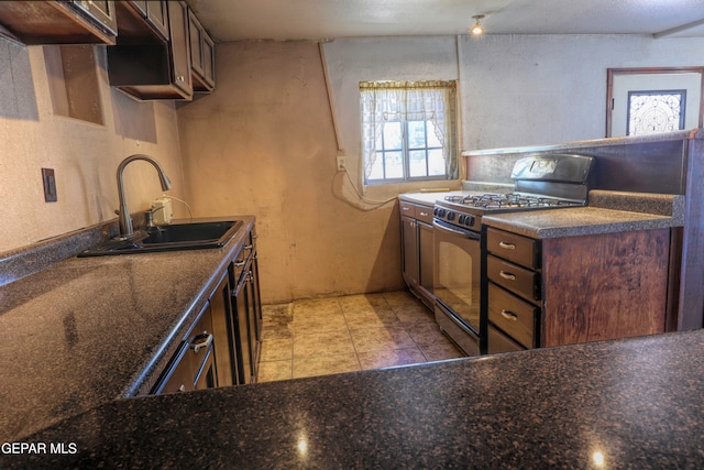 kitchen featuring sink, dark brown cabinetry, black gas range oven, and dark stone counters