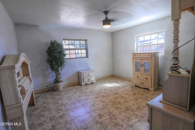 interior space featuring ceiling fan, a textured ceiling, and multiple windows