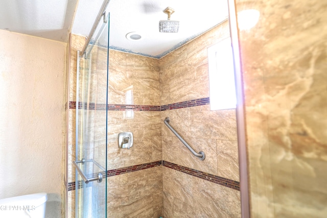 bathroom featuring toilet and a shower with shower door