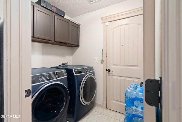 laundry room with cabinets, a textured ceiling, separate washer and dryer, and light tile patterned floors