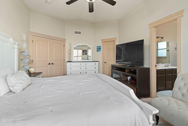 carpeted bedroom with a closet, ensuite bath, sink, and ceiling fan