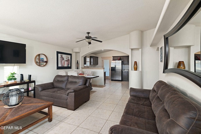 living room featuring a textured ceiling, ceiling fan, and light tile patterned floors