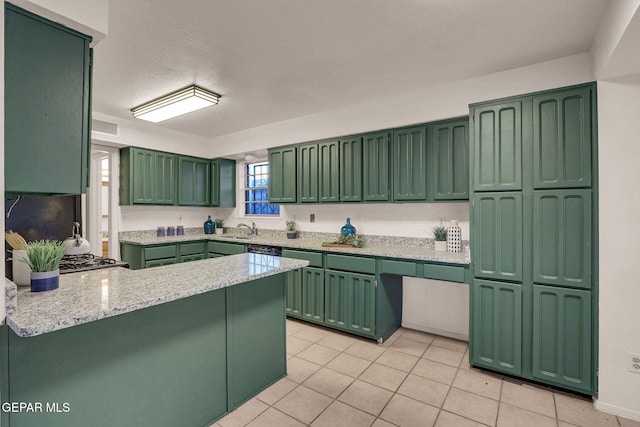 kitchen featuring light stone countertops, sink, green cabinetry, kitchen peninsula, and light tile patterned floors