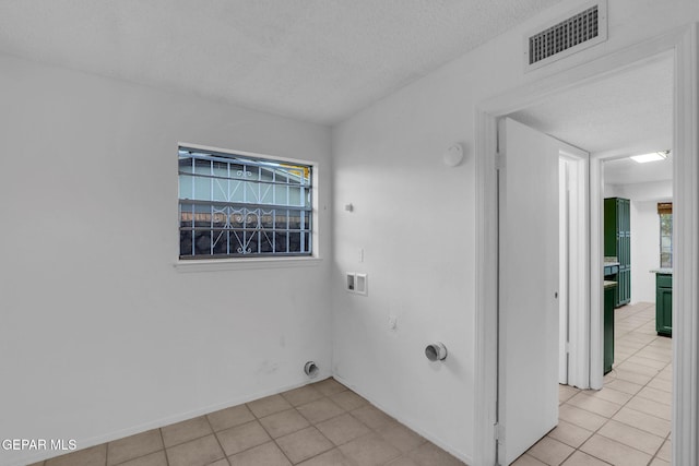 laundry area featuring hookup for an electric dryer, light tile patterned flooring, a textured ceiling, and washer hookup