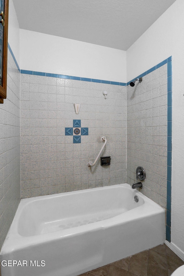 bathroom with tiled shower / bath combo and tile patterned flooring