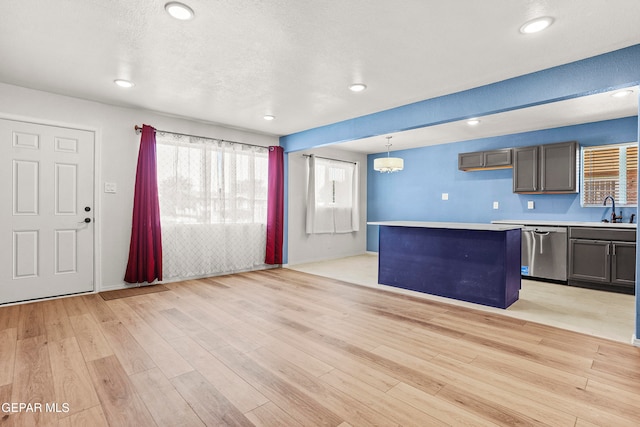 kitchen with stainless steel dishwasher, a kitchen island, pendant lighting, and light hardwood / wood-style floors