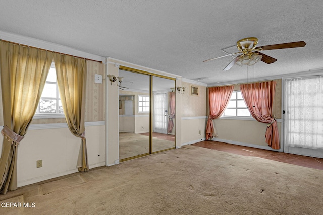 unfurnished bedroom featuring ceiling fan, light carpet, and a textured ceiling