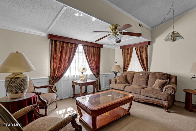 living room with ceiling fan, ornamental molding, a textured ceiling, and light colored carpet