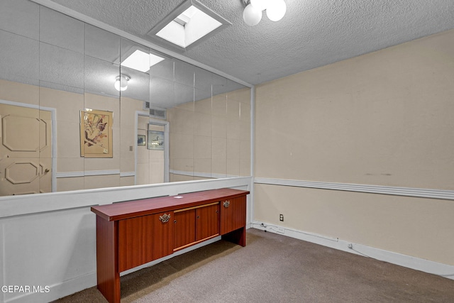 misc room with a textured ceiling and dark colored carpet