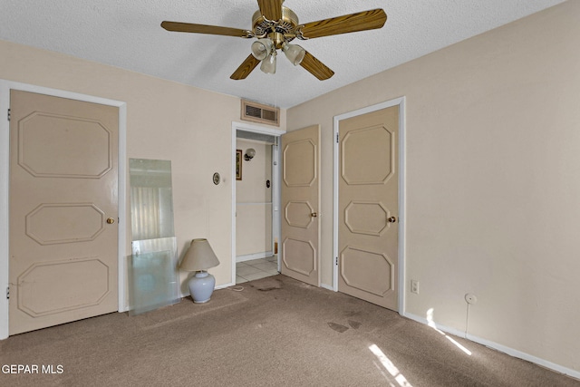 unfurnished bedroom featuring a textured ceiling, carpet floors, and ceiling fan