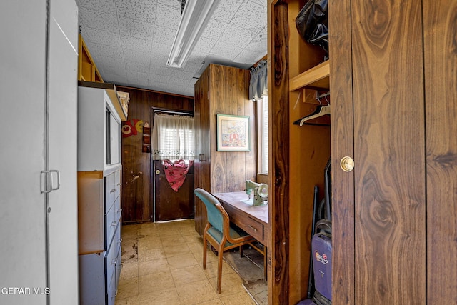 office space with a paneled ceiling and wood walls