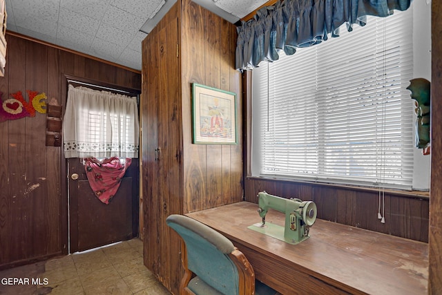 dining space featuring wood walls and a drop ceiling